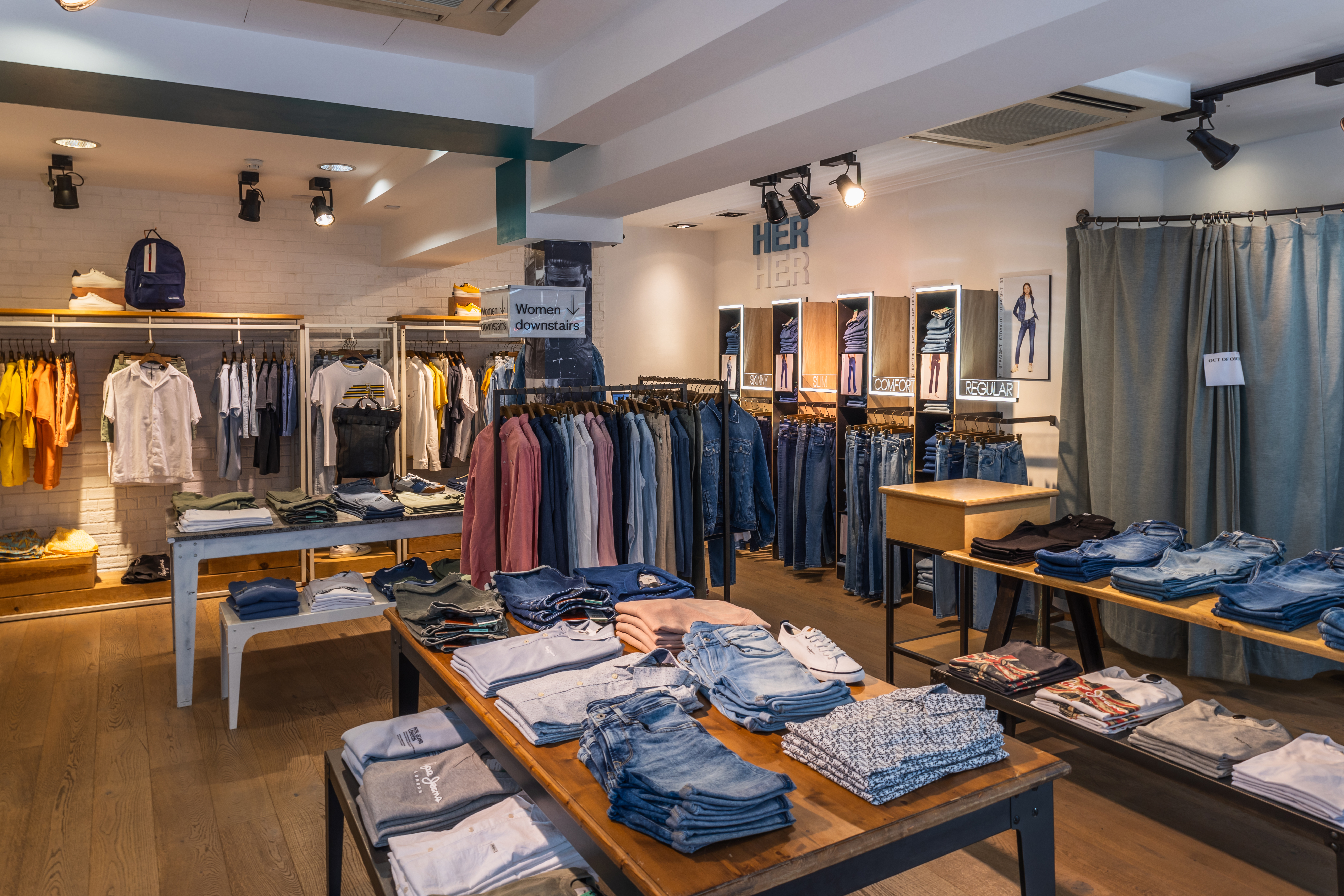 A stylish clothing store interior showcasing folded fashionwear, modern racks, and vibrant lighting. London, UK, 21 May 2023